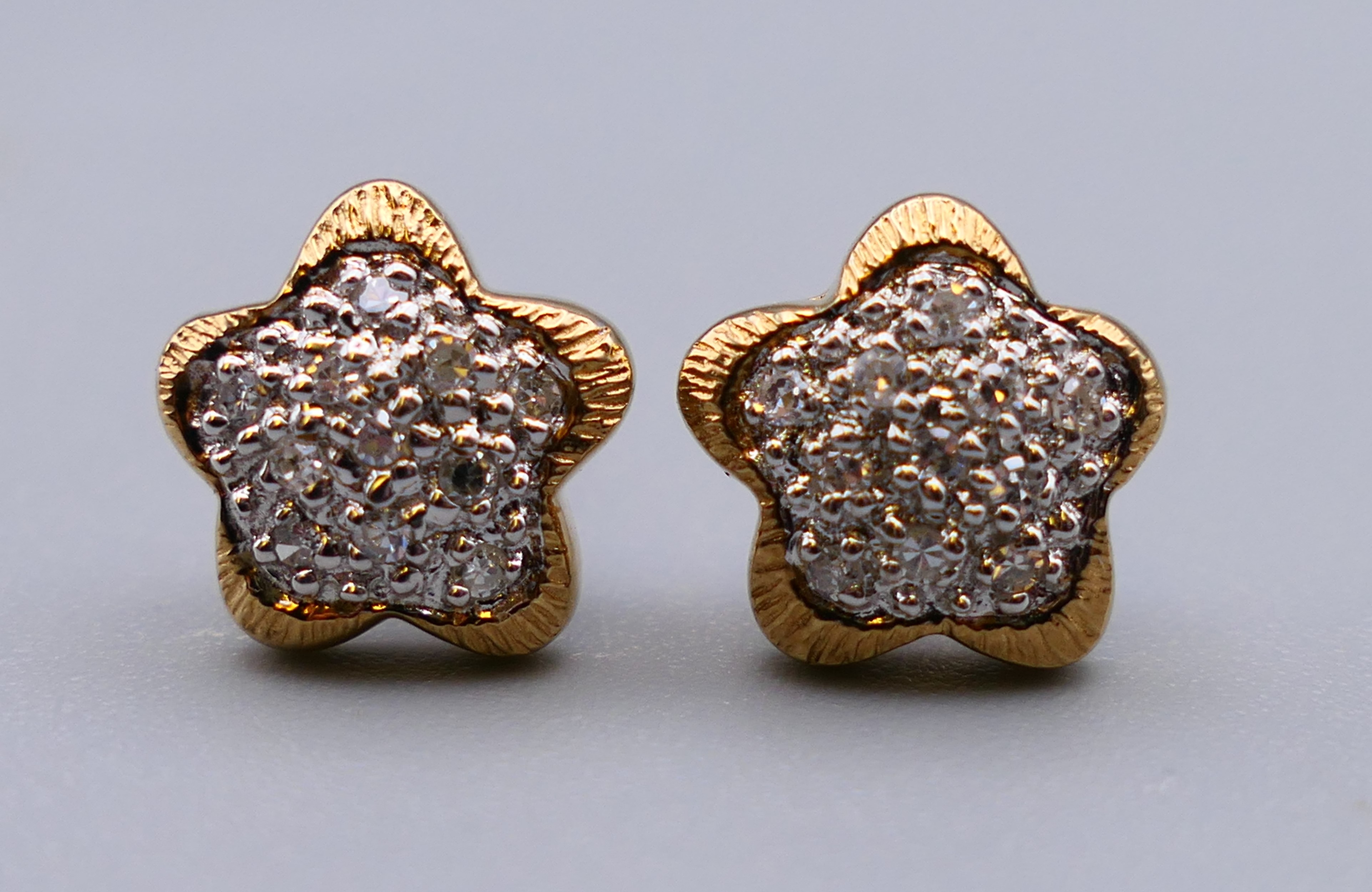 A pair of 9 ct gold diamond star shaped cluster earrings. 1 cm diameter. 1.8 grammes total weight.