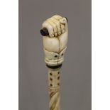 A 19th century carved whalebone walking stick with carved ivory clenched fist handle. 80 cm long.