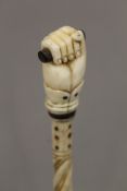 A 19th century carved whalebone walking stick with carved ivory clenched fist handle. 80 cm long.