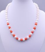 A pearl and coral bead necklace with a 14 ct gold clasp. 40 cm long.