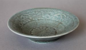A small Chinese celadon bowl, the underside decorated with calligraphy. 14 cm diameter.