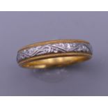 A 22 ct gold and engraved platinum wedding ring. Ring size P. 5.4 grammes total weight.