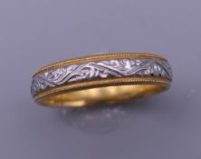 A 22 ct gold and engraved platinum wedding ring. Ring size P. 5.4 grammes total weight.