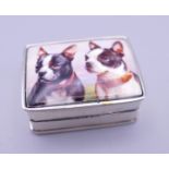 A silver pill box depicting dogs. 3 cm wide.