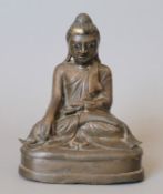 An antique, possibly 18th century, bronze model of Buddha, with inset glass eyes. 16 cm high.