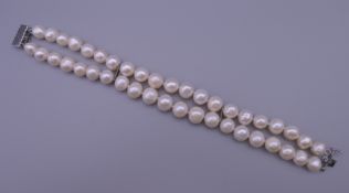 A two-strand pearl choker with 14 K white gold clasp. 20 cm long.