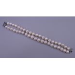 A two-strand pearl choker with 14 K white gold clasp. 20 cm long.