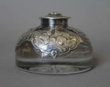 A silver mounted inkwell embossed with cherubs. 6 cm high.