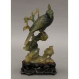 A Chinese carved jade model of birds mounted on a carved wooden stand. 15 cm high overall.