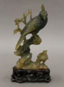 A Chinese carved jade model of birds mounted on a carved wooden stand. 15 cm high overall.