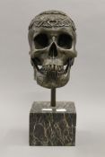 A bronze skull on a marble base. 35 cm high.