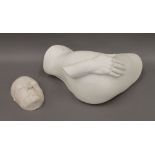 A plaster sculpture of a hand on a buttock and a plaster cast of a human face.