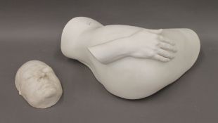 A plaster sculpture of a hand on a buttock and a plaster cast of a human face.