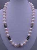 An 18 ct white gold mounted and diamond section pearl necklace. 50 cm long.