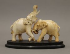An early 20th century Indian carved ivory model of two elephants mounted on a horn plinth base.