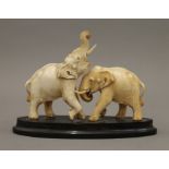 An early 20th century Indian carved ivory model of two elephants mounted on a horn plinth base.