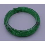 A carved jade bangle. 6 cm interior diameter.