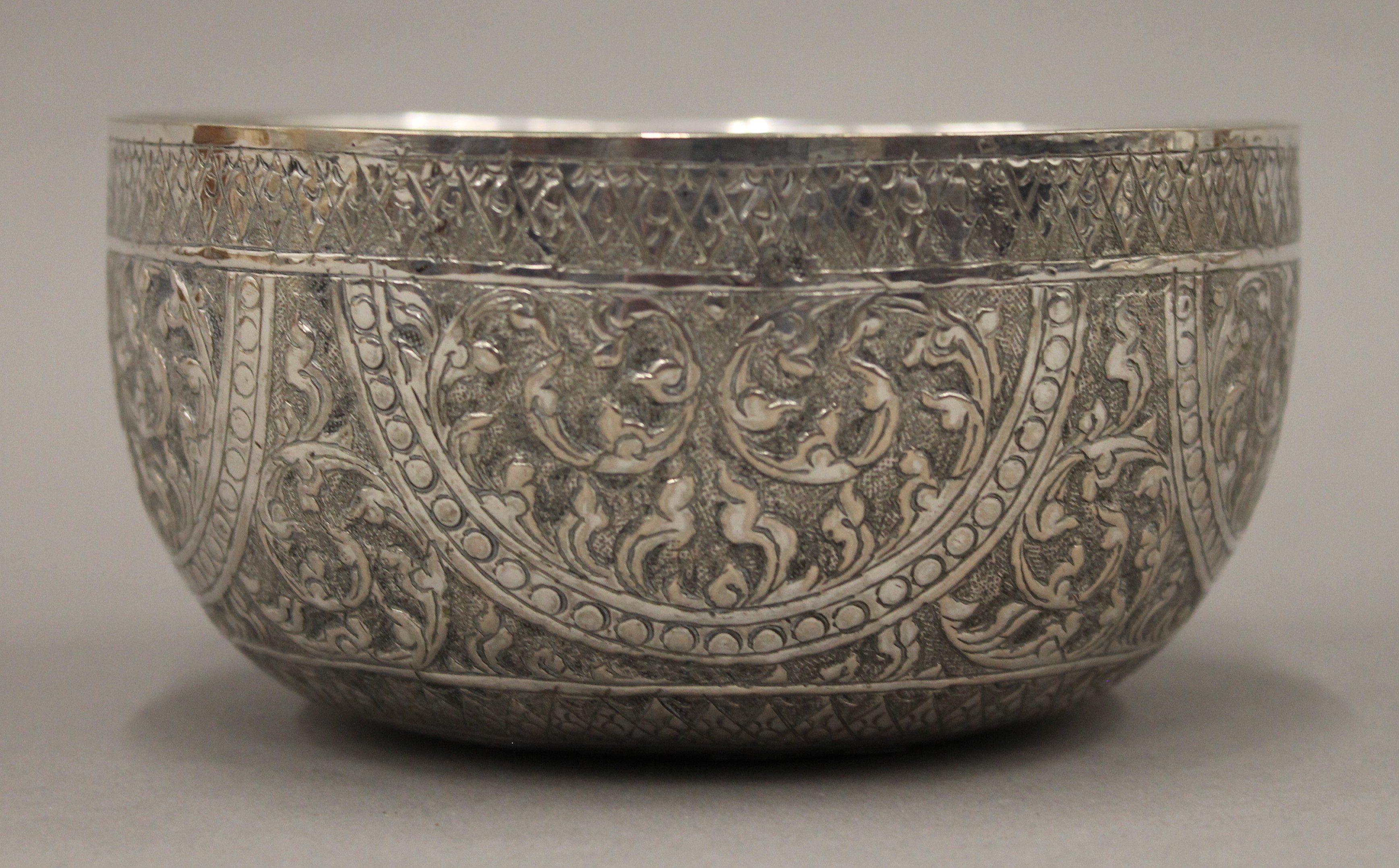 A 19th century hand tooled Thai silver bowl, stamps to base. 14 cm diameter. 115 grammes. - Image 2 of 3