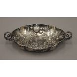 An Augsburg twin handled silver dish, heavily decorated with castle and church to centre,