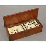 A boxed set of bone and ebony dominoes. The box 19.5 cm wide.