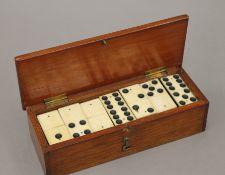 A boxed set of bone and ebony dominoes. The box 19.5 cm wide.