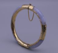 A lavender jade and gilt bangle. 6 cm inner diameter.