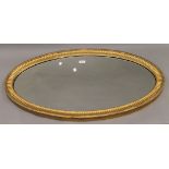 A 19th century oval gilt framed mirror. 90 cm wide, 53 cm high, 3.5 cm deep.