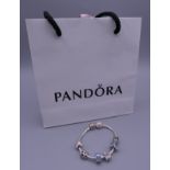 A Pandora silver charm bracelet in a Pandora bag. Approximately 20 cm long.