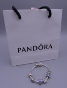 A Pandora silver charm bracelet in a Pandora bag. Approximately 20 cm long.