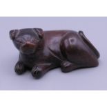 A carved wooden netsuke in the form of a dog. 5.5 cm long, 2.5 cm high.