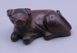 A carved wooden netsuke in the form of a dog. 5.5 cm long, 2.5 cm high.