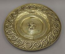 An antique brass alms dish with the central motif of a rampant lion, hook for suspension.