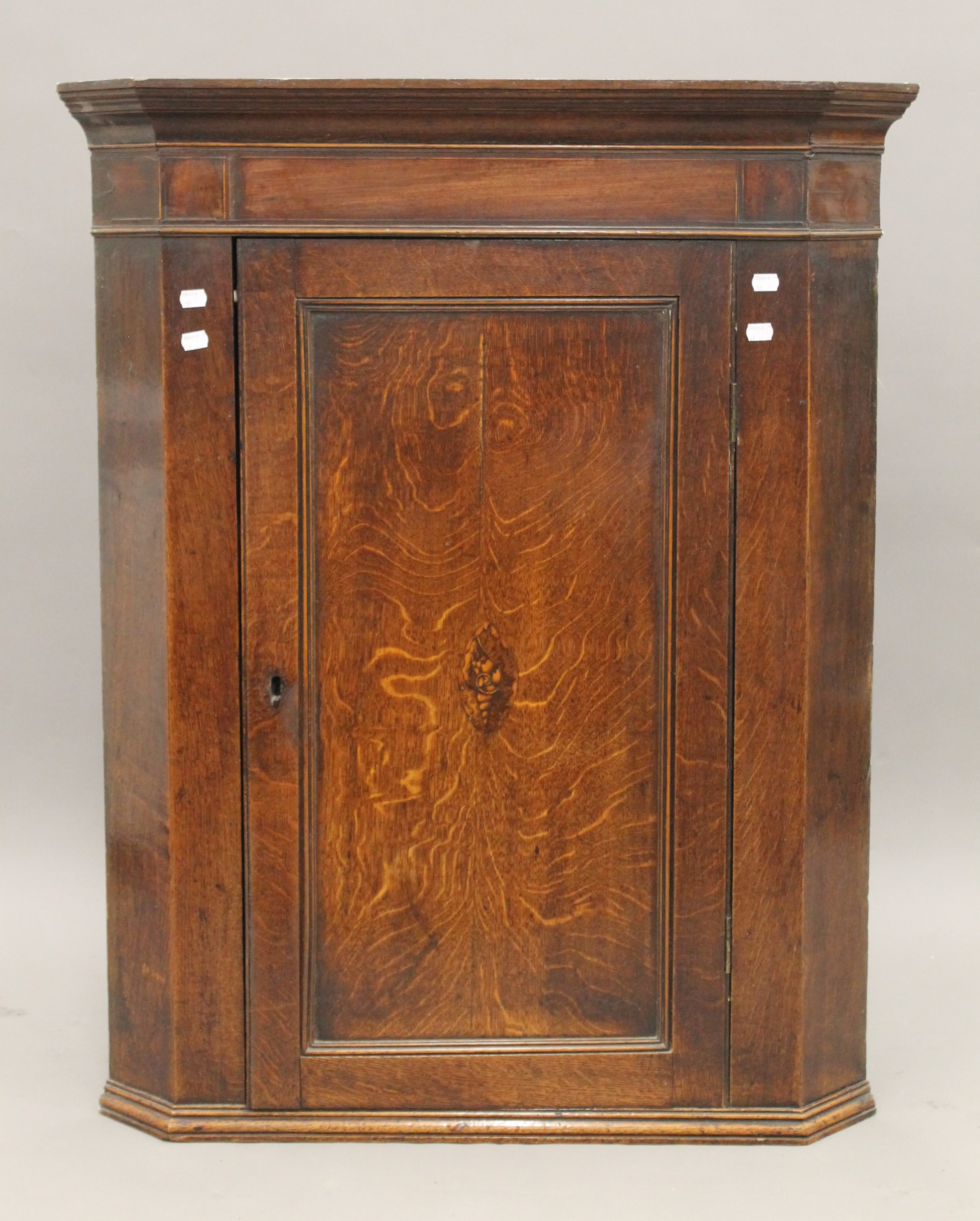 A George III inlaid oak and mahogany corner cupboard. 85 cm wide.