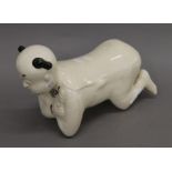 A Chinese porcelain pillow formed as a kneeling boy. 35 cm long.