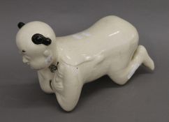 A Chinese porcelain pillow formed as a kneeling boy. 35 cm long.