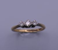 An 18 ct gold and platinum three stone diamond ring. Ring size P. 2.7 grammes total weight.