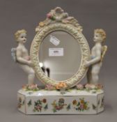 A porcelain mirror decorated with cherubs. 27 cm high.