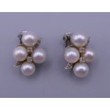 A pair of 14 K white gold, pearl and diamond clip-on earrings. 2 x 1.5 cm. 7.