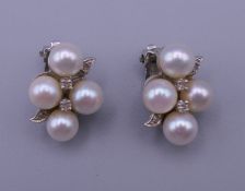 A pair of 14 K white gold, pearl and diamond clip-on earrings. 2 x 1.5 cm. 7.