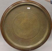 A large Kufic script Islamic brass tray on wooden back. 75 cm diameter overall.