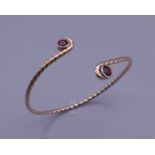 A 9 ct gold and garnet Celtic bracelet. 7 cm diameter. 13.4 grammes total weight.