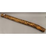 A carved wooden didgeridoo. 109 cm long.