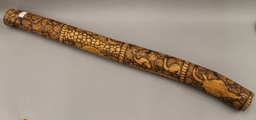 A carved wooden didgeridoo. 109 cm long.