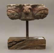 A carved stone figural mask capitol, possibly Medieval, mounted on a display plinth. 18 cm wide.