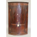 A Georgian mahogany bowfront hanging corner cupboard. 113.5 cm high.