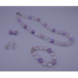 An amethyst and rock crystal bead necklace, a matching bracelet and two pairs of matching earrings.
