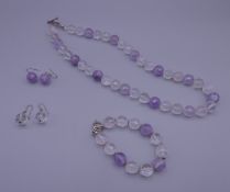An amethyst and rock crystal bead necklace, a matching bracelet and two pairs of matching earrings.