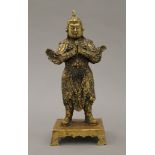 A gilded bronze Chinese figure of a warrior on a shaped rectangular base. 23 cm high.