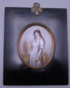 A porcelain plaque depicting 'Ruth the Gleaner' standing holding a sheaf of wheat, in a black frame.