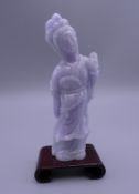 A lavender jade carving of Guanyin, on a small wooden stand. 11 cm high overall.